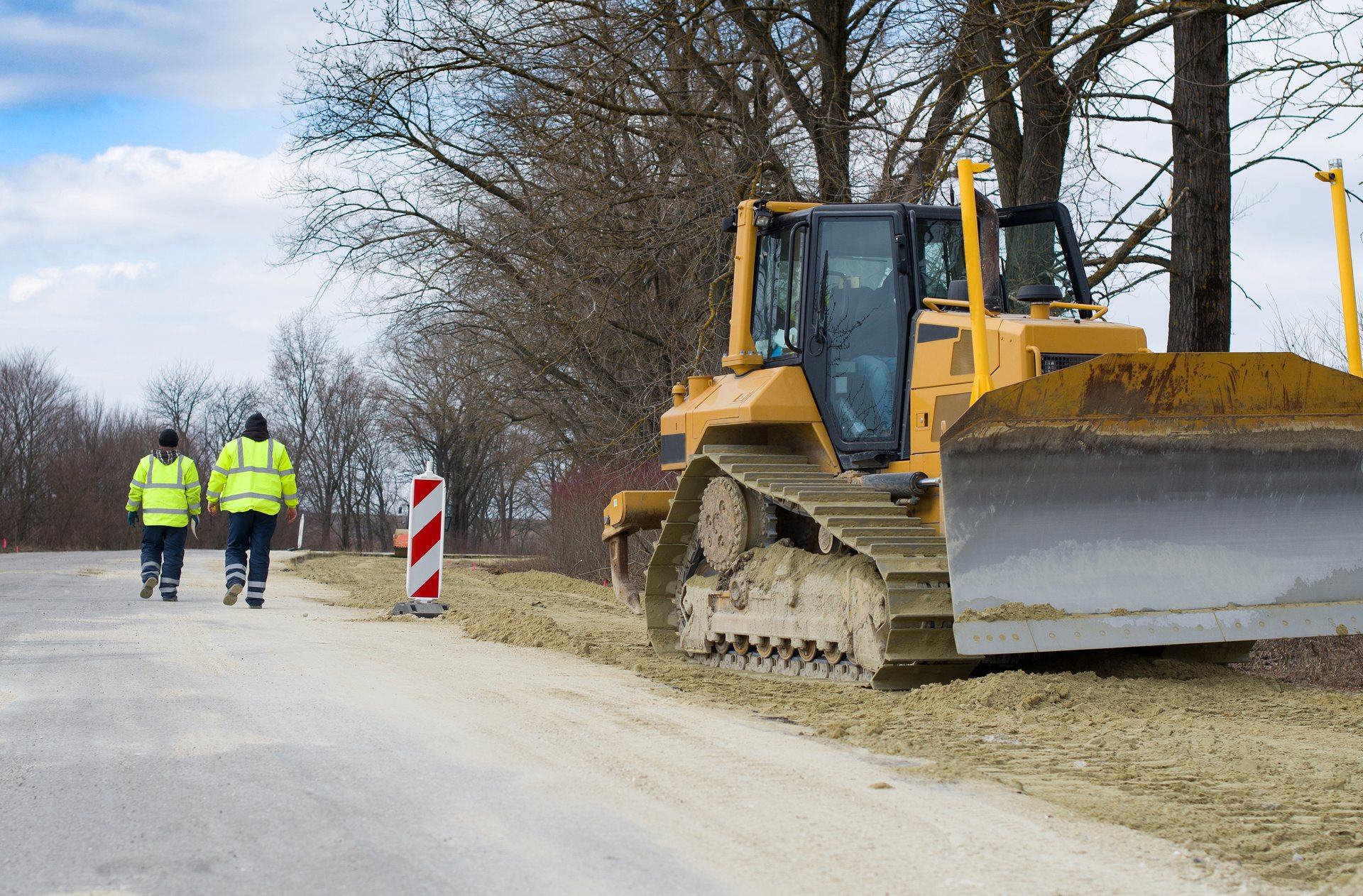 Bouteur sur une route en travaux, agents en gilets haute visibilité